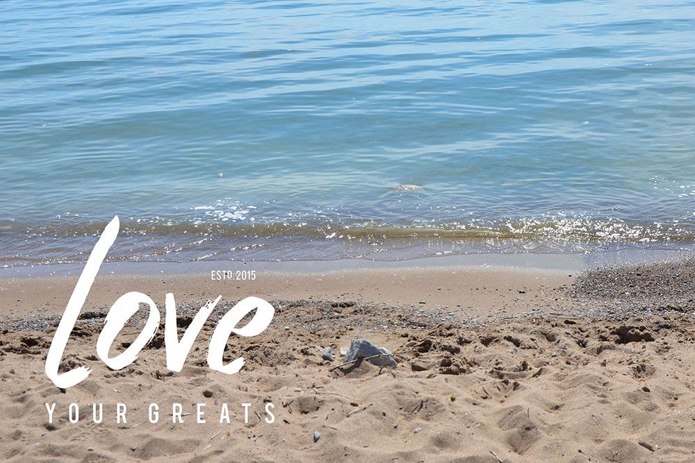 Love Your Greats logo wordmark on a Lake Huron beach photo.
